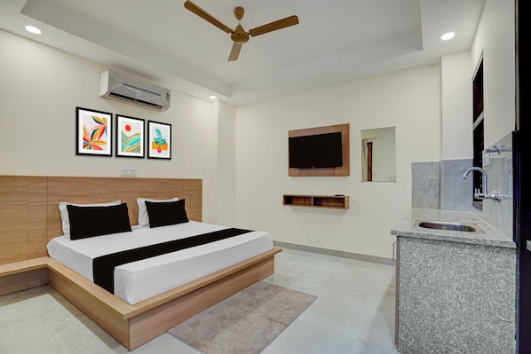 A modern hotel room with a bed, ceiling fan, air conditioning unit, artwork, TV, and a bathroom with a sink and mirror. - Hotel O D'Empire (Gurugram)