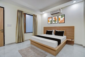 A modern bedroom with a wooden bed frame, a large window with curtains, an air conditioning unit, and three framed artworks on the wall. - Hotel O D'Empire (Gurugram)