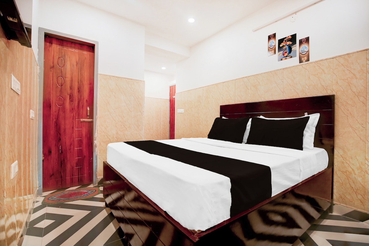 A hotel room with a bed, a wooden door, a red wall, and a marble wall.