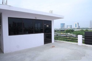 A modern building with large windows and a flat roof, overlooking a busy road with vehicles and other buildings in the background. - Hotel O the Front Door (Gurugram)