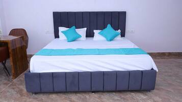 Una cama con cabecera oscura, ropa de cama blanca y dos almohadas turquesas.