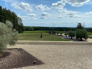 A landscaped outdoor area with a gravel path, a grassy field, and a variety of trees.