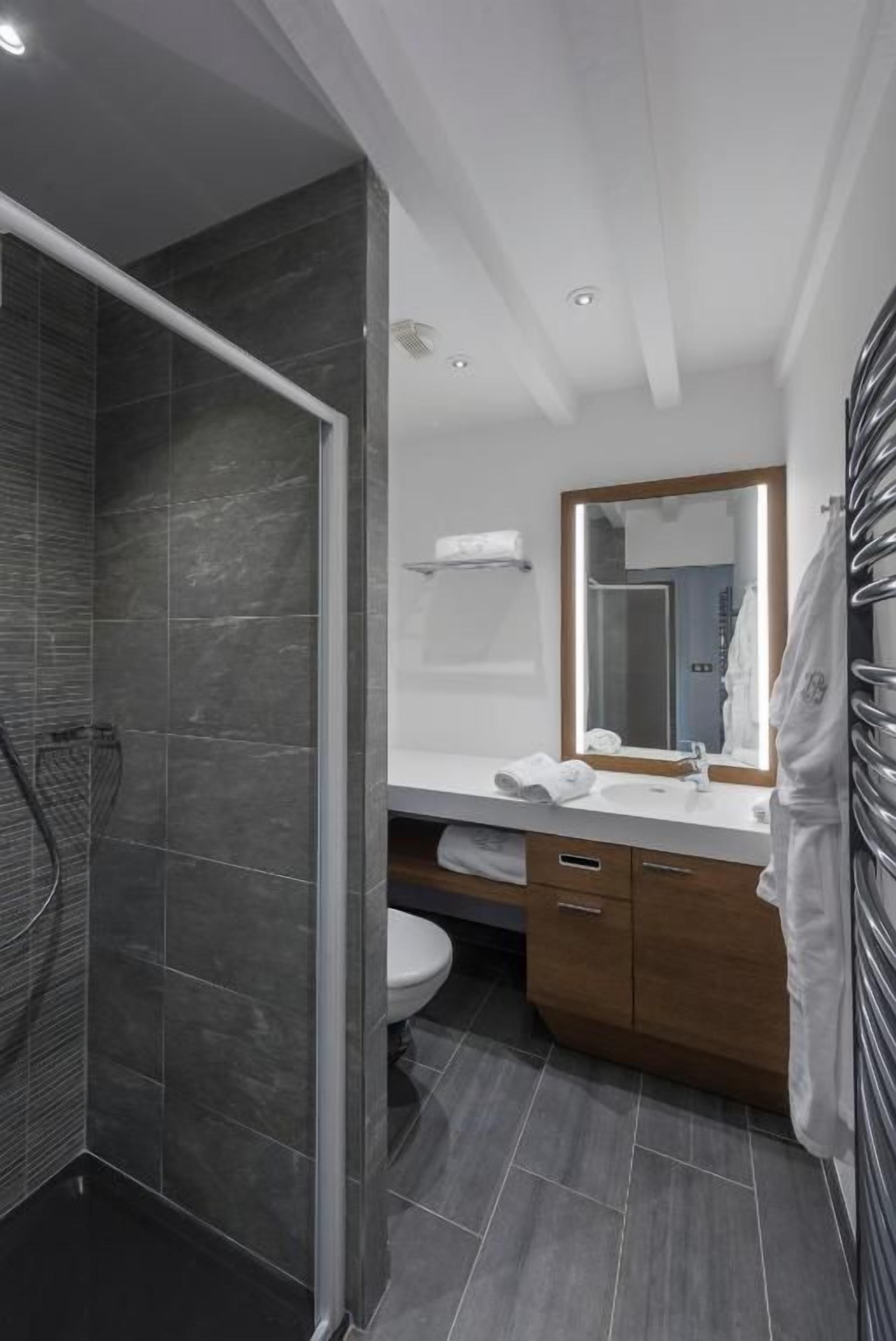 A modern bathroom with a glass shower enclosure, a white sink, and a wooden vanity.