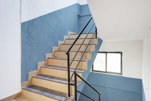 Una escalera con una pared azul a un lado y una ventana al otro.