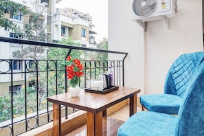 A balcony with a table, chairs, and a hanging flower arrangement. - Hotel O Nisarg Villa (Pune)