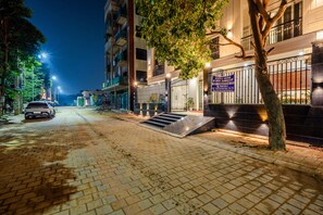 Ein nächtlicher Straßenblick mit einem Gebäude, das einen verschlossenen Eingang, eine Treppe und ein geparktes Auto zeigt.