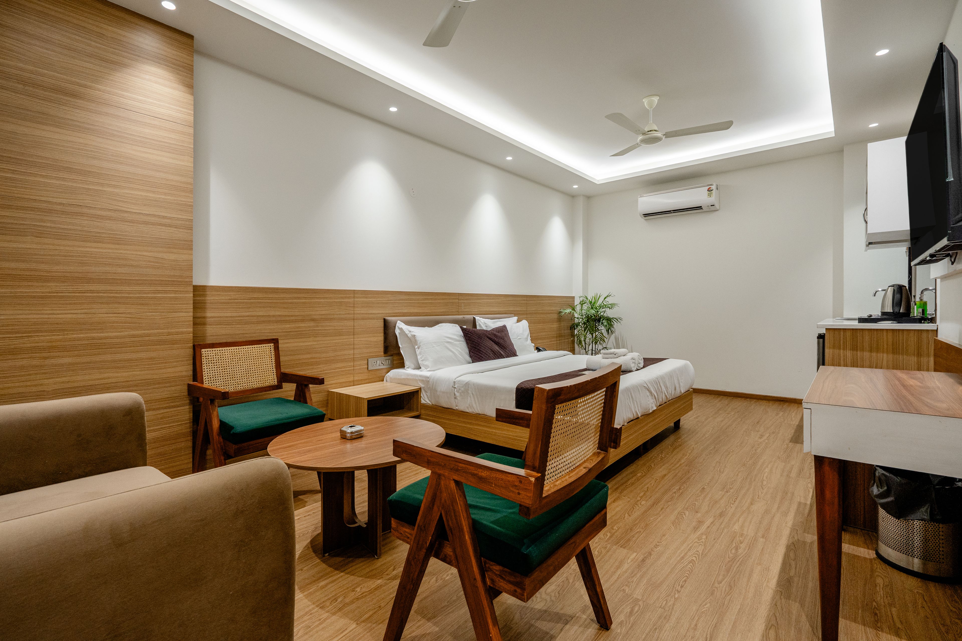Ein Hotelzimmer mit einem Bett, einem Schreibtisch, einem Sessel, einem kleinen Tisch und einem Deckenventilator.