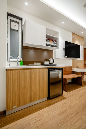 A modern kitchen with a built-in dishwasher, a coffee maker, and a flat-screen TV mounted on the wall. - Aristo Grand Hotel Near Golf Course Rd (Gurugram)