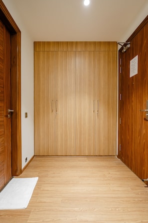 Ein Flur mit Holzboden, der zu einem großen Holzschrank mit zwei Türen und einer kleinen Fußmatte führt.