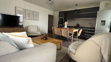 A modern living room with a sofa, armchair, and a dining table with chairs.