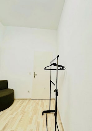 A room with a wooden floor, a black coat rack, and a closed door. - Vienna Hideaway Private Room for Two (Wien)