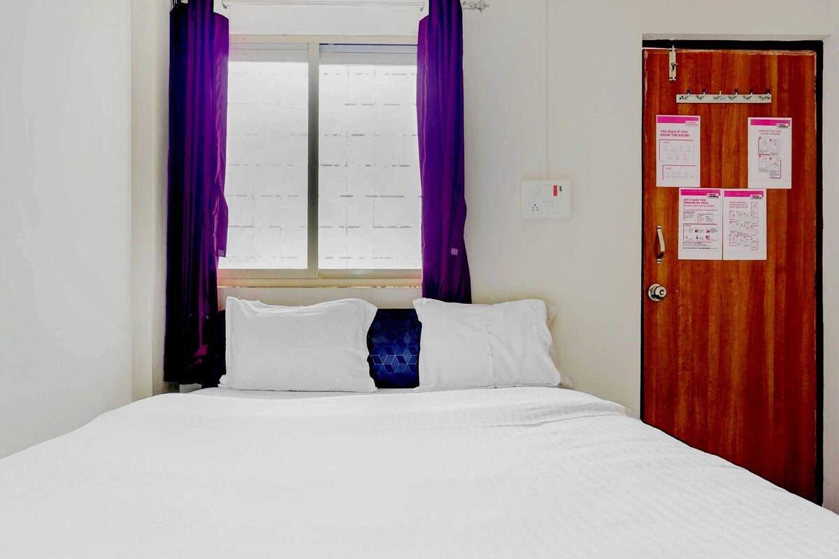 Ein Hotelzimmer mit einem Bett, einem Fenster mit violetten Vorhängen und einer Tür mit angebrachten Aushängen.