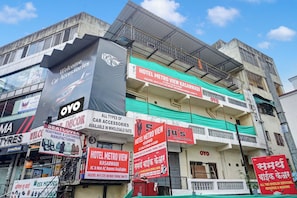 Un edificio de varios pisos que alberga diversos establecimientos comerciales, como una tienda de accesorios para automóviles, un hotel y un taller de reparación de motocicletas.