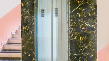 Una escalera que conduce a un ascensor con un muro de mármol.