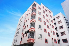 Un edificio de varios pisos con balcones, ventanas con rejas de metal y un cielo despejado.
