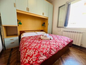 A bedroom with a bed, a wardrobe, a window, and a radiator. - New Listing (Sanremo)