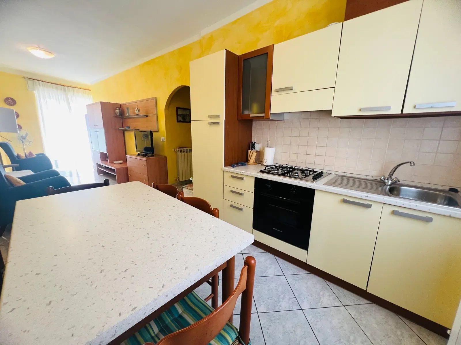 A compact kitchen with a dining table, chairs, and basic appliances.