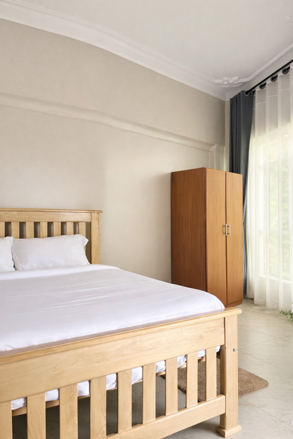 Quarto com cama de madeira, guarda-roupa e janela com cortinas.