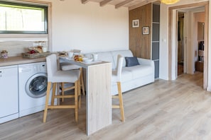 Cocina compacta con lavadora, comedor con mesa y sillas, y sala de estar con sofá.