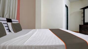 A hotel room with a large bed, a dresser, and a mirror.