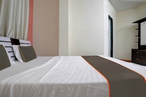A hotel room with a large bed, a dresser, and a mirror. - Hotel O Krupa Lodge (Pune)