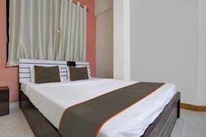 A neatly made bed with a white and brown bedspread, a wooden headboard, and two pillows. - Hotel O Krupa Lodge (Pune)