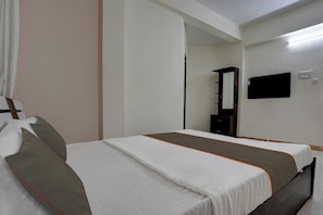 A hotel room with a bed, a mirror, a television, and a wardrobe. - Hotel O Krupa Lodge (Pune)