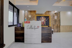 A reception desk with a 'Collection' sign, a 'No Smoking' sign, a wall-mounted calendar, and a religious statue. - Hotel O Krupa Lodge (Paud)