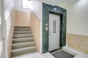 A staircase leading to a door with a keypad lock, a small window above, and a carpeted entrance. - Hotel O Krupa Lodge (Paud)
