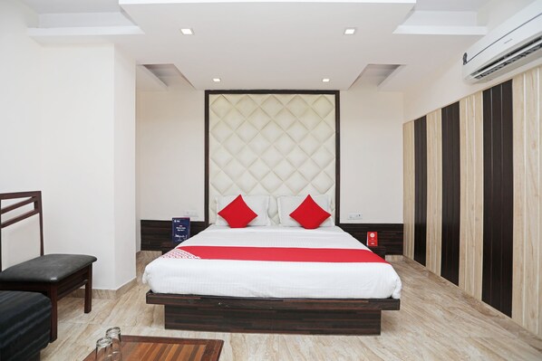 A modern hotel room with a large bed, a wooden bench, a bedside table, and a wardrobe. - Hotel O Subhadra Residency (Meerut)