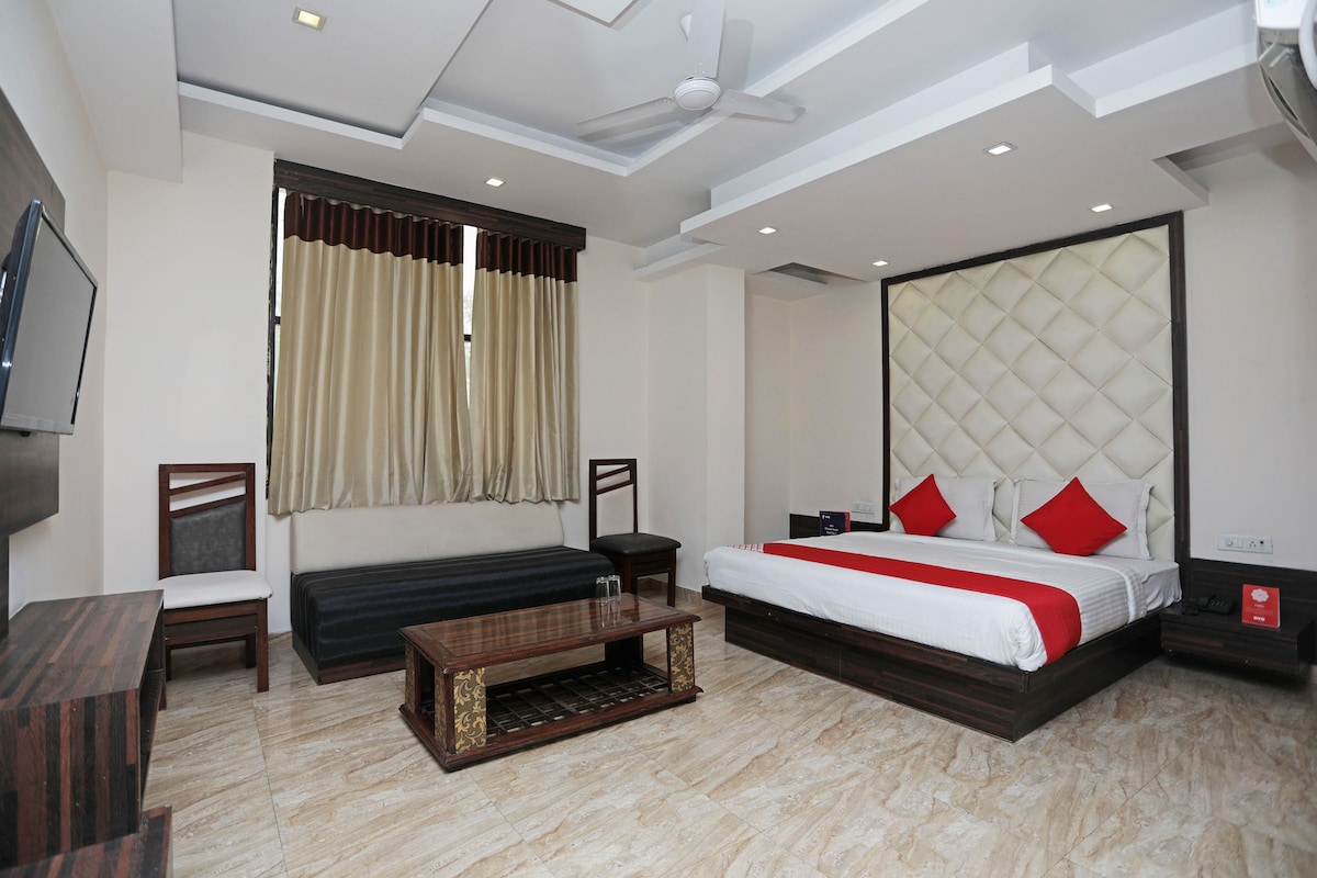A modern hotel room with a bed, bedside tables, a TV, a sofa, and a ceiling fan.