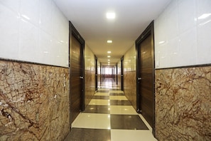 Un pasillo con suelo a cuadros, paredes de mármol y puertas que dan a varias habitaciones.