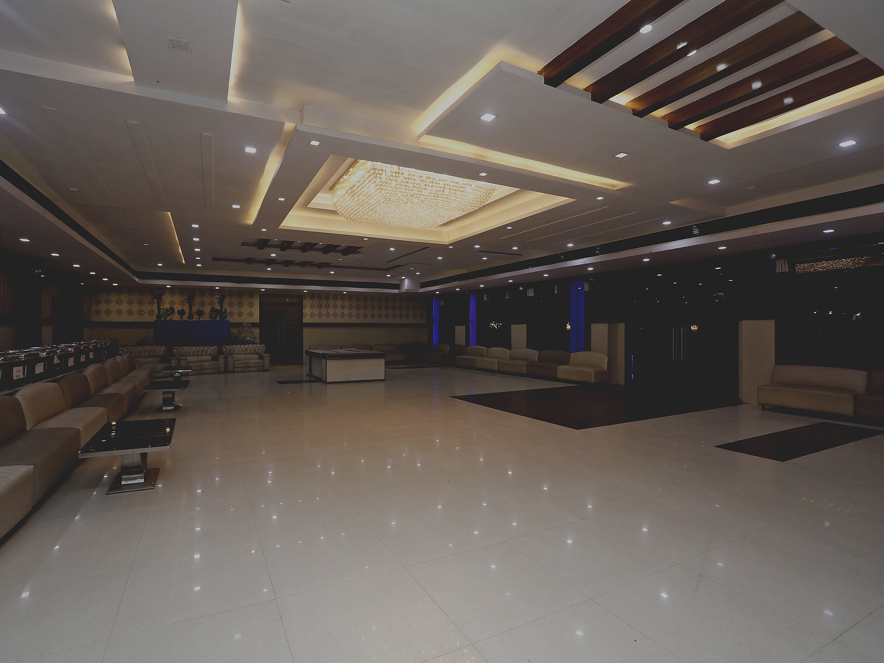 A spacious lobby with a high ceiling, recessed lighting, and a central seating area with sofas and tables.