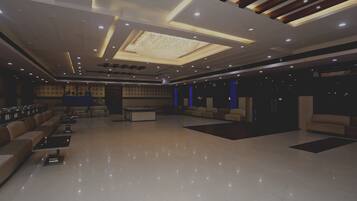 A spacious lobby with a high ceiling, recessed lighting, and a central seating area with sofas and tables.