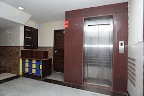 Un ascensor con pantalla digital, una puerta con un letrero rojo y una pared de azulejos.