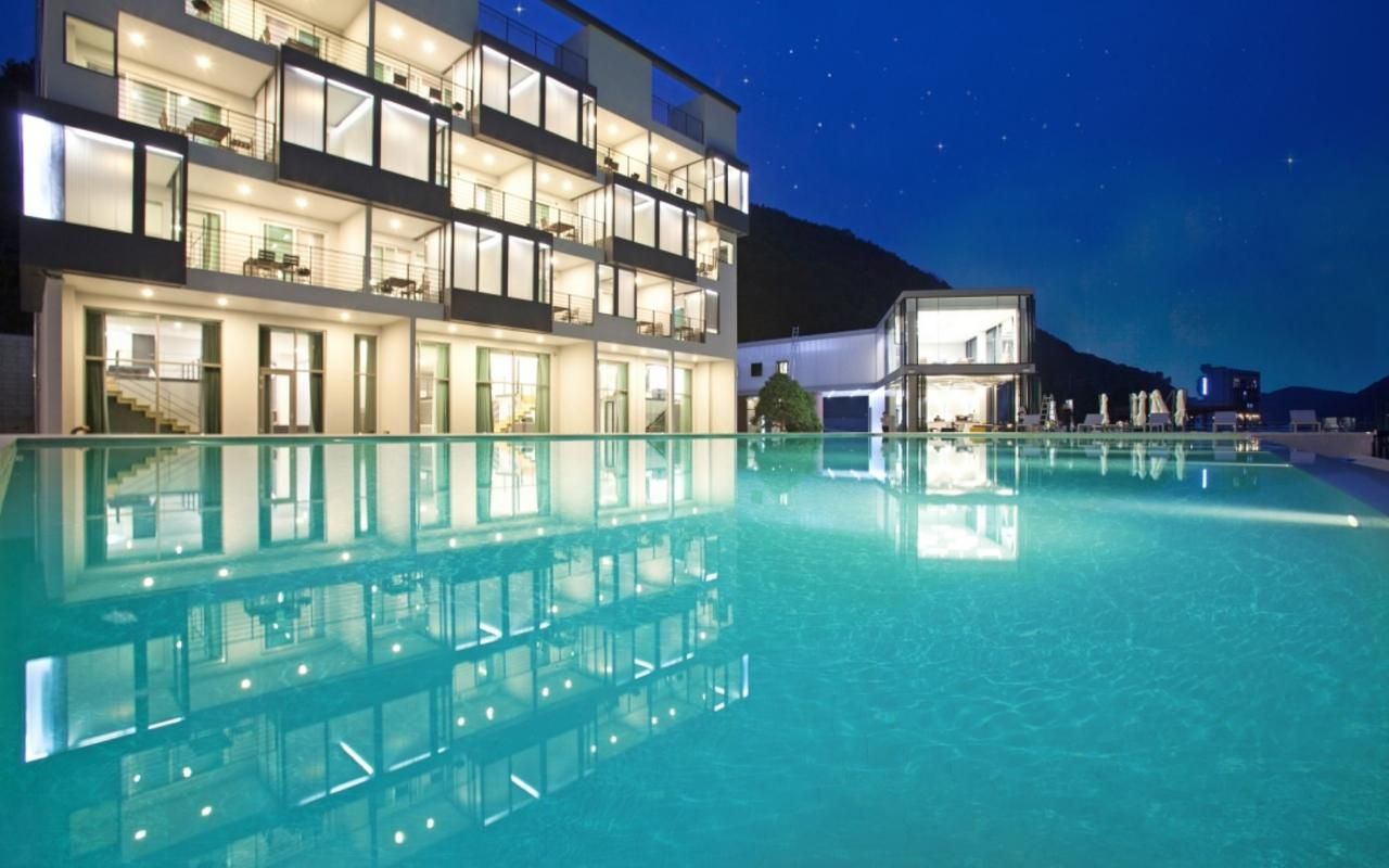 Un hôtel à plusieurs étages doté d’une piscine, de balcons et offrant une vue sur les montagnes.