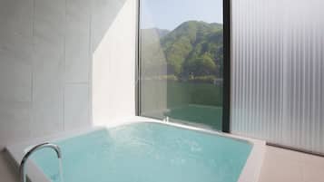 Un baño moderno con una bañera grande y vistas a un lago y montañas.