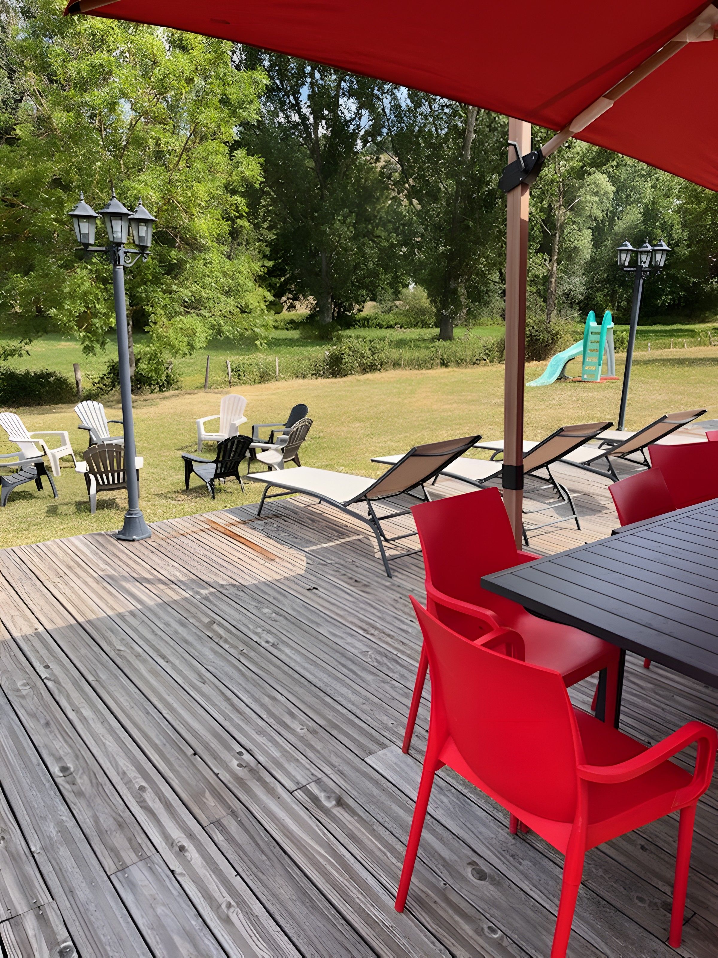 Eine Terrasse im Freien mit Holzboden, roten und weißen Stühlen und einem Tisch.