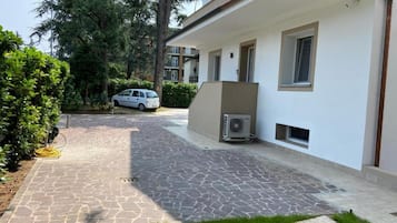 Un edificio residenziale con vialetto lastricato, un'auto parcheggiata e un condizionatore d'aria.