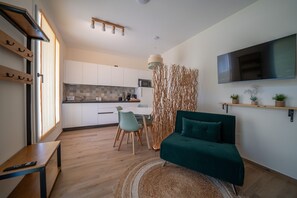Un soggiorno moderno con angolo cottura, zona pranzo e TV a parete.