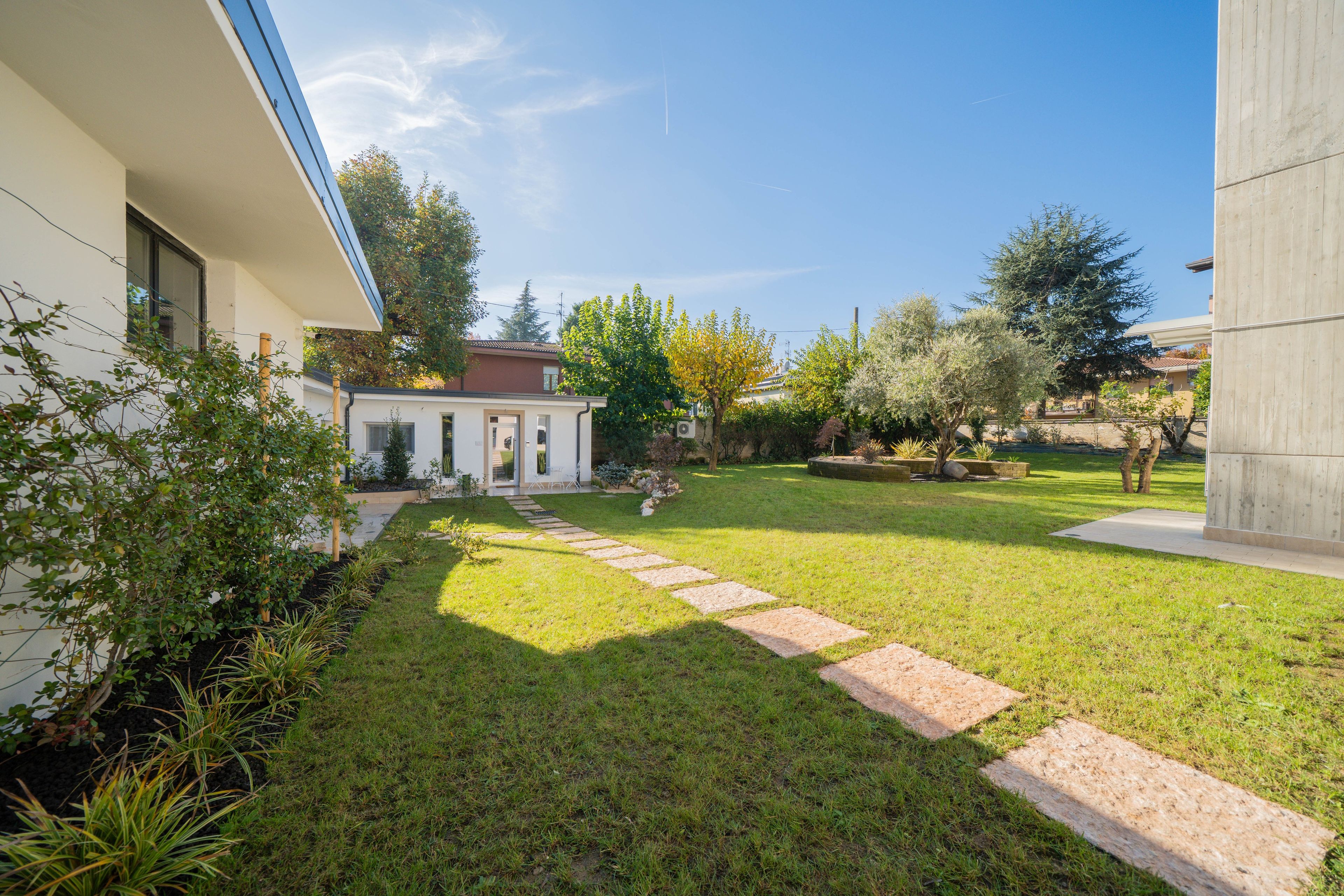 A modern house with a well-maintained lawn, a stone pathway, and a small garden area.