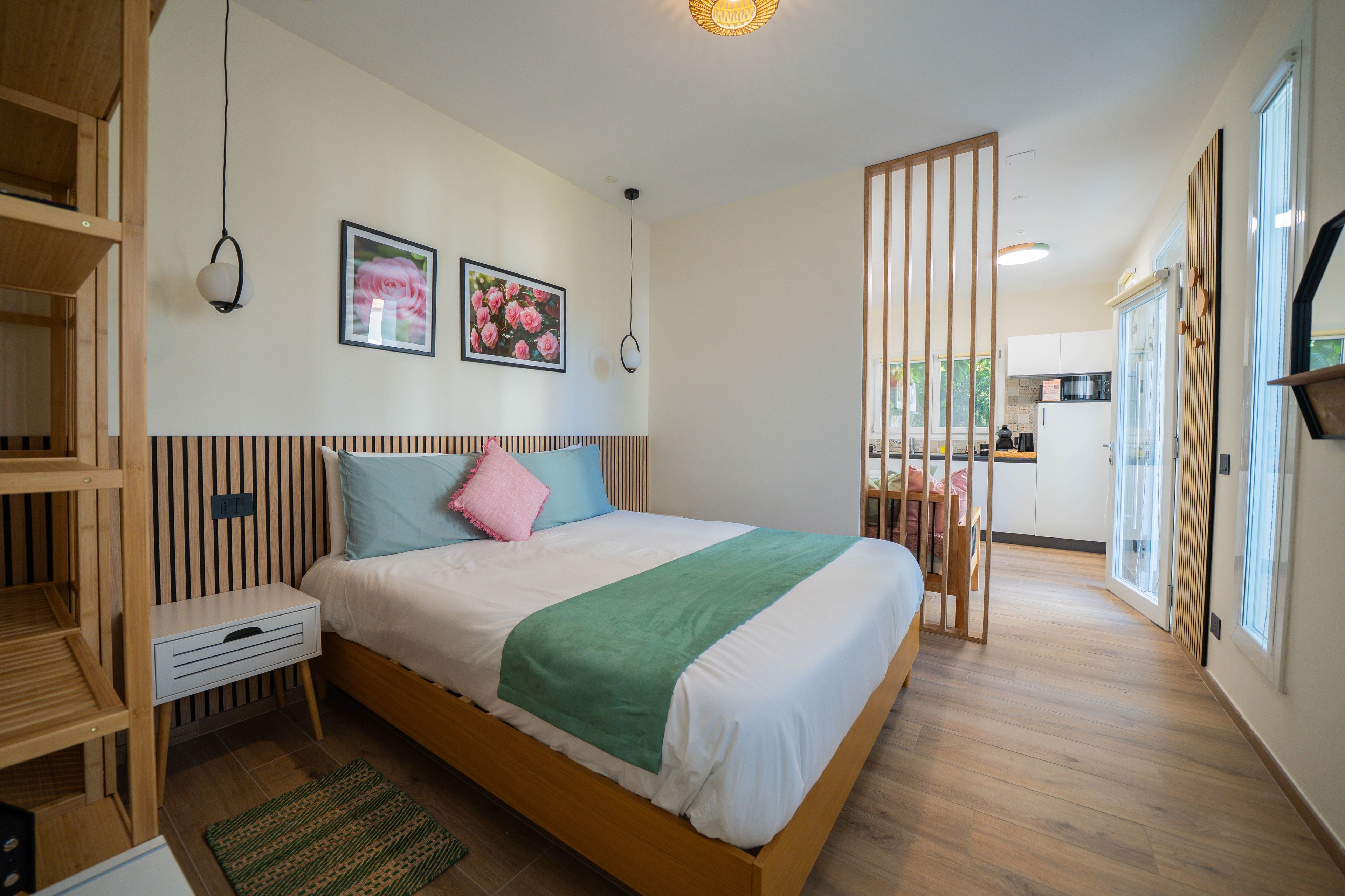 Una camera da letto moderna con un letto in legno, un comodino, due quadri appesi alla parete e una coperta verde.