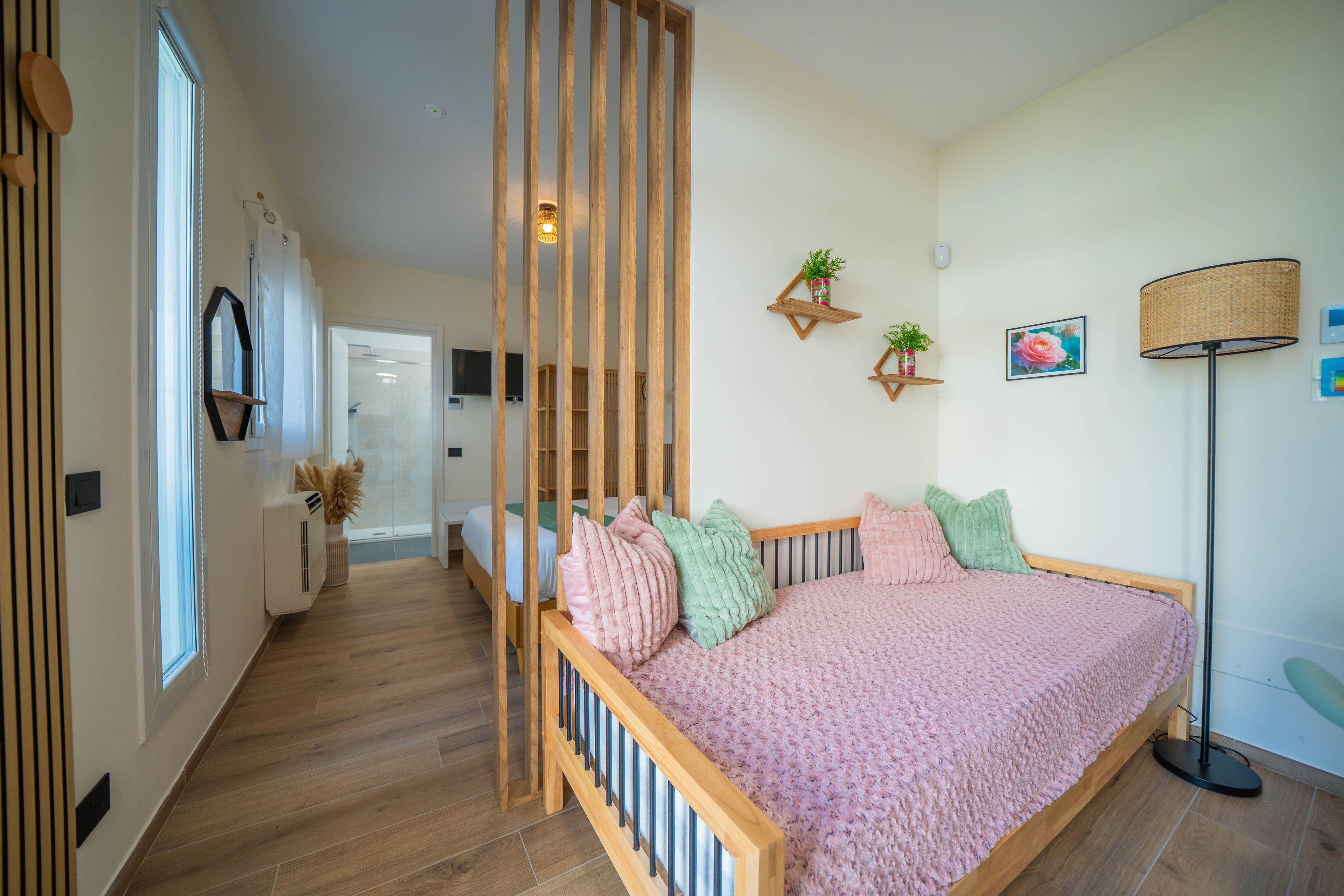 A bedroom with a wooden bed frame, a pink blanket, and a bedside lamp.