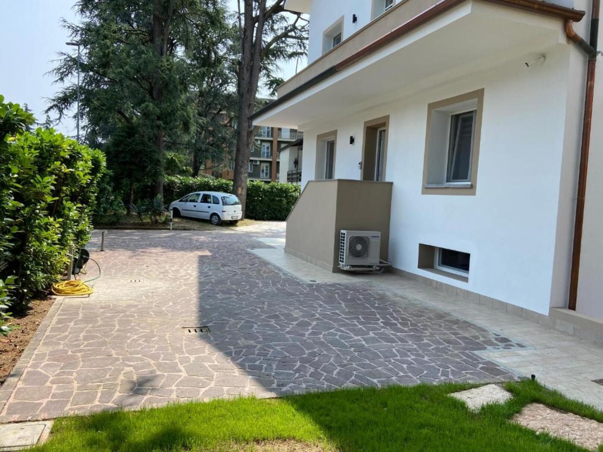Un edificio residenziale con vialetto lastricato, un'auto parcheggiata e un condizionatore d'aria.