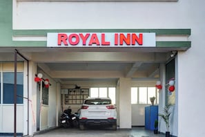 Entrada al Royal Inn con una camioneta SUV blanca estacionada adentro.