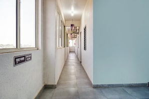 Un pasillo con un letrero que indica el segundo piso, una decoración floral colgante y una ventana a la izquierda.