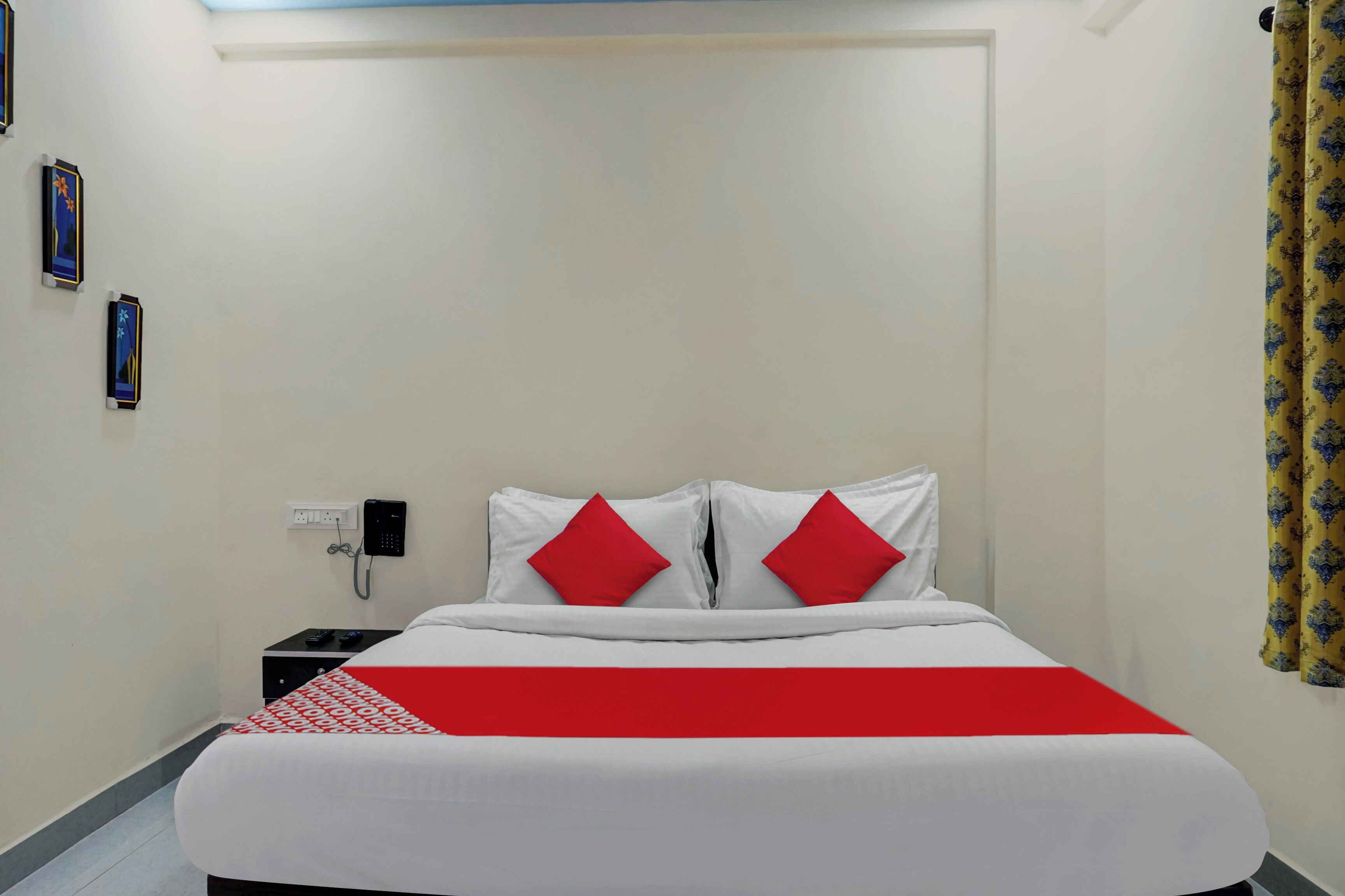 Habitación de hotel con una cama, una mesita de noche, un teléfono y un enchufe.