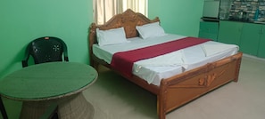 Une pièce avec un lit, une petite table ronde et un mur vert.