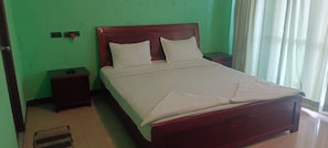A single bed with a wooden headboard, a nightstand, and a wall socket. - Lake Palace Home Stays  (Yercaud , Salem)