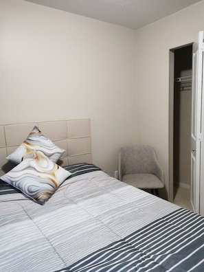 Une chambre à coucher avec un lit, des oreillers, une chaise et une armoire.